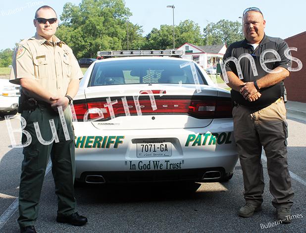 Captain Brian Vandiver (left) and Sheriff John Doolen (right) stand by the first patrol car to bear the new stickers ‘In God We Trust’.