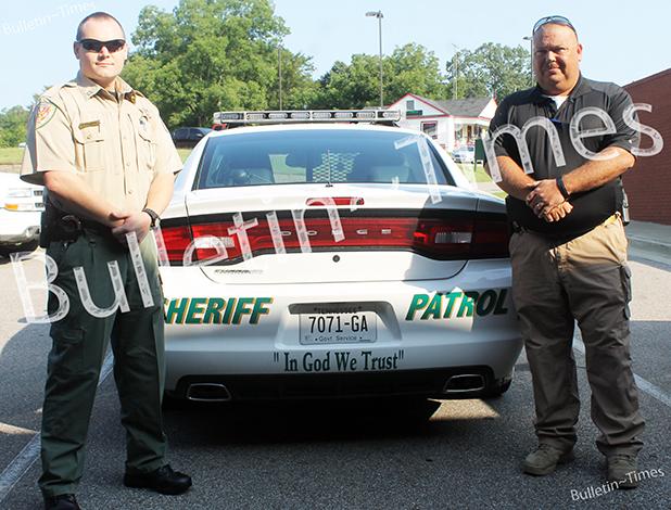 Sheriff department proclaims ‘In God We Trust’ Captain Brian Vandiver (left) and Sheriff John Doolen (right) stand by the first patrol car to bear the new stickers ‘In God We Trust’.