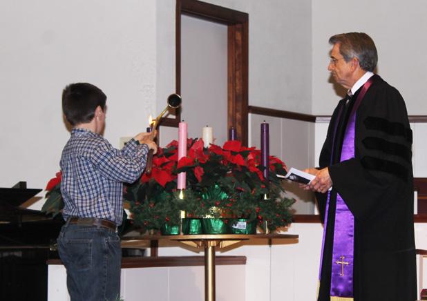 Noah Cody (left) lights the Advent Wreath of First United Methodist Church during the Ecumenical Service on Sunday, November 30 as Dr. Paul Clayton watches.