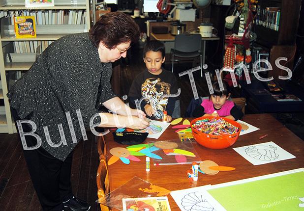 Wanza Taylor, head librarian at Grand Junction, helps Patrick and Kylee Sarogham with a craft project.