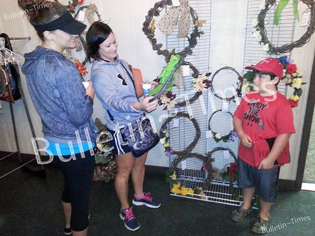 Jennifer Sinclair, Amanda Clutter, and Jayce Clutter (l to r) admire handmade door wreaths offered at the Grand Valley Lakes Ladies Club Annual Yard Sale. The unusual wreaths were fashioned from vines found in the Valley.   