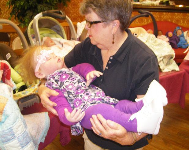 Even in seeing it’s still hard to believe Volunteer Betty Thompson carries Haileigh to a waiting resident at a Pine Meadows therapy session.