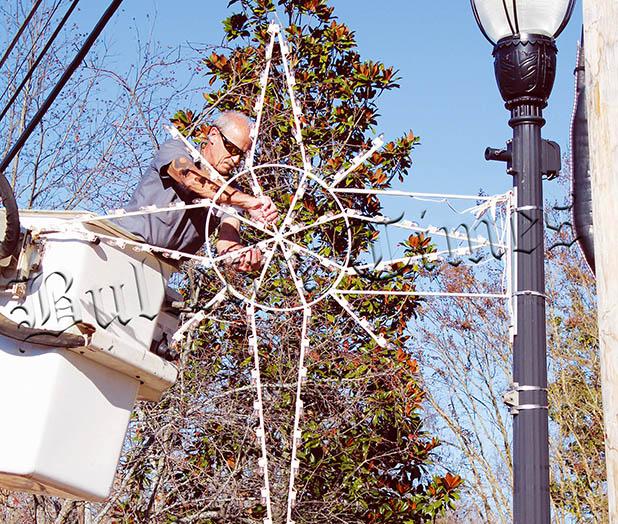 Ricky Galloway operates from the bucket truck to secure Christmas stars and snowflakes in Bolivar.