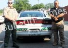 Captain Brian Vandiver (left) and Sheriff John Doolen (right) stand by the first patrol car to bear the new stickers ‘In God We Trust’.