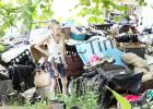 Dixie Hills Resident Mary Cole stands in the midst of the garbage and items in her front yard, angry, while county employees work to clean up her property after she refused to comply with cleanup herself.